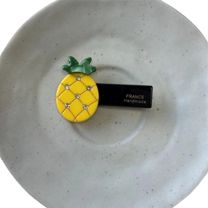 Sparkling pineapple hair clip with yellow rhinestones and green leaves on a black base