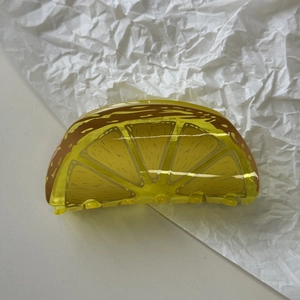 Minimalist translucent yellow lemon slice hair claw clip made of resin on white background