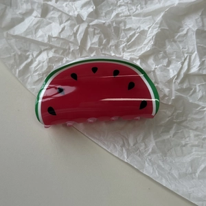 Detail of a watermelon claw clip made of glossy acrylic with seed pattern and red finish