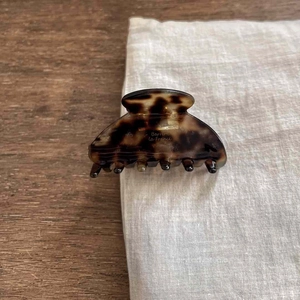 Macro shot of tortoise shell acetate hair claw clip with golden brand engraving
