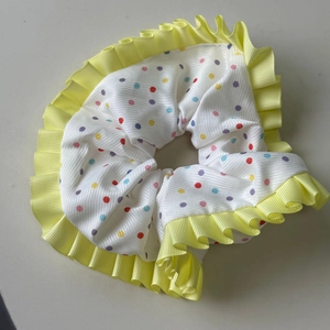 Close-up of colorful polka dot scrunchie with vibrant yellow pleated ruffled edges