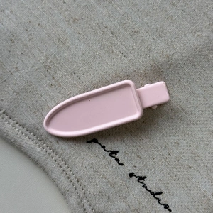 Close-up of pink geometric metal hair clip with smooth matte finish on linen background