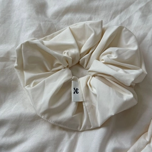 Detailed macro view of cream oversized scrunchie fabric texture and minimalist logo tag