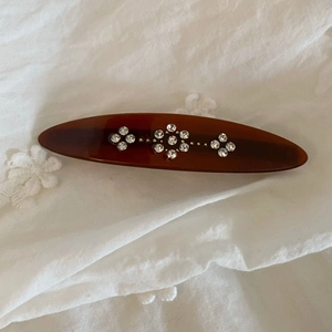 Detail of tortoise shell hair clip with crystal flowers on vintage white fabric