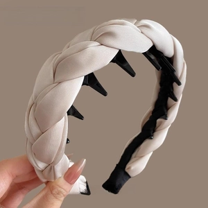 Détail du serre-tête tressé en satin beige avec peigne intérieur pour une tenue fixe