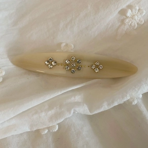 Macro shot of French vintage acetate hair clip with floral rhinestones on white fabric