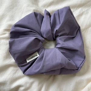 Detail shot of a purple cotton scrunchie with soft twill texture and logo label