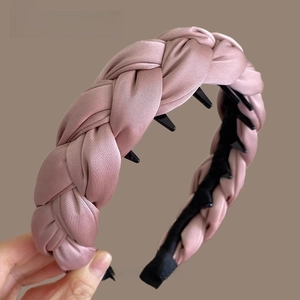 Détail d'un serre-tête en satin tressé rose clair avec dents antidérapantes internes
