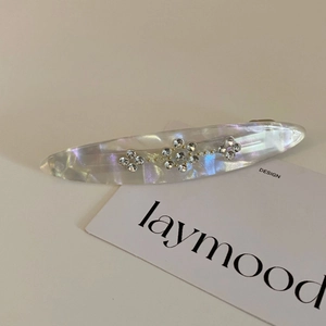 Detail of slim acetate hair clip with sparkling rhinestone floral patterns and shell-like texture