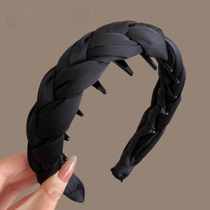Détail du serre-tête tressé en satin noir montrant les dents et la texture du tissu