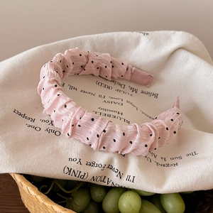 Gros plan sur le tissu à pois roses du serre-tête avec détails plissés et froufrous