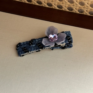 Detailed macro view of denim hair clip with crystal flower and silver metal base