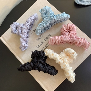 Elegant pleated satin claw clips in five pastel colors arranged on a vintage book