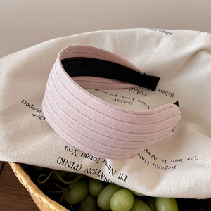 Détail d'un serre-tête plissé rose clair sur un panier tressé avec des raisins verts