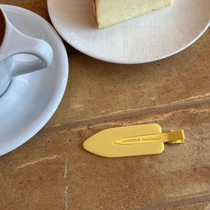 Matte yellow candy-colored oversized hair clip on a stone tabletop for women