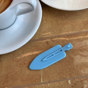 Detail of light blue matte hair clip on a café table for fixing hair bangs and styling