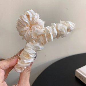 Close-up of cream-colored pleated fabric hair claw clip with satin texture finish