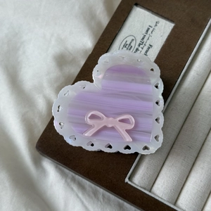 Detail view of heart-shaped acetate claw clip with pink bow and white lace edges