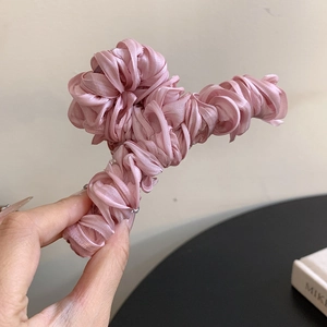 Detailed view of the pleated pink satin fabric texture on the elegant hair claw clip