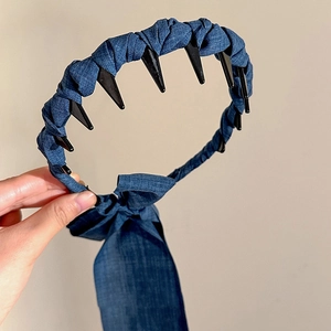 Détail d'un serre-tête en denim bleu avec dents de peigne et longs rubans noués