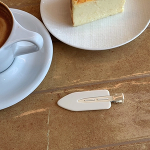 Close-up of white minimalist candy-colored hair clip on a cozy cafe wooden table