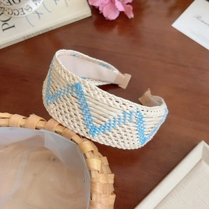 Detailed weave pattern on bohemian cream and blue straw headband over wooden desk