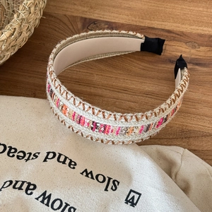 Bohemian woven wide headband with colorful embroidery on a rustic wooden background