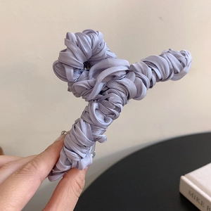 Detail of purple satin claw clip with a twisted pleated fabric design for hair