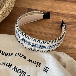 Close-up of bohemian woven wide headband with intricate straw and fabric stitching