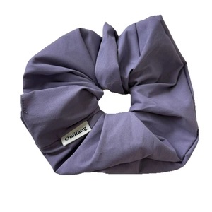Lilac purple scrunchie in twill fabric with a small white woven label on white background