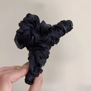 Close-up of black pleated fabric flower hair claw clip with a subtle glossy finish