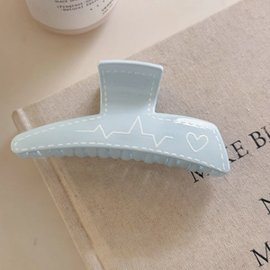 Pince à cheveux minimaliste bleu clair motif cœur avec couture blanche sur lin beige