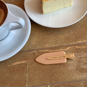 Detail of nude matte flat hair clip on table with coffee and cheesecake background
