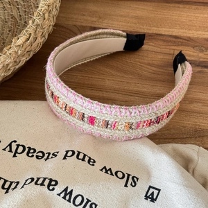 Bohemian woven raffia headband with colorful patterned embroidery on wood background