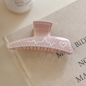 Gros plan détaillé d'une pince à cheveux rose avec motif cœur sur toile beige