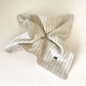 Detailed texture of striped beige fabric scrunchie with a small black heart charm