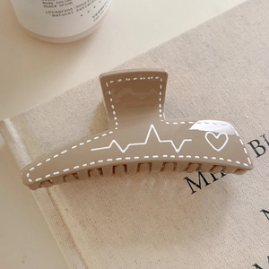 Détail de la pince à cheveux trapèze avec motif cœur sur fond en lin beige naturel
