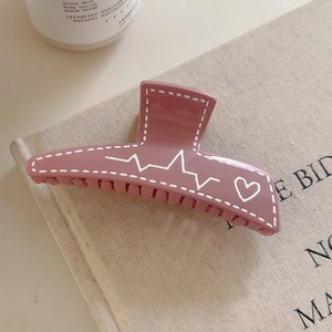 Grosse pince à cheveux rose poudré avec graffitis de cœurs blancs et motif de ligne d'impulsion