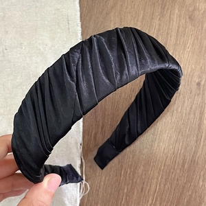 Detailed texture of black satin pleated wide headband for women showing glossy fabric folds
