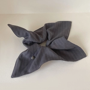 Close-up of dark grey striped fabric scrunchie featuring a delicate heart-shaped ornament