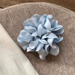 Eleganter hellblauer Satin-Blüten-Haargummi mit Schichtblütenblättern auf Leinen