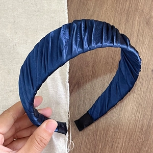 Detail view of navy blue pleated satin headband with fine vertical folds and smooth texture