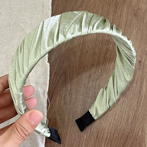 Detail showing pale green pleated satin headband with elegant ruched texture and light sheen