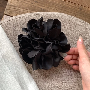 Nahaufnahme von schwarzem Satin Haargummi mit Blütenblättern auf gewebter Matte