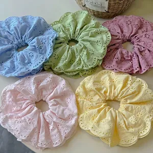 Five macrame eyelet hair scrunchies in pastel colors with scalloped lace edges