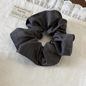 Détail du chouchou en tissu gris foncé avec pendentif cœur sur fond de dentelle