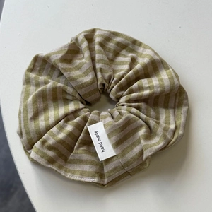 Detailed macro view of olive green striped fabric scrunchie with hand made woven label