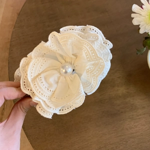 Detailed close-up of white lace flower hair clip with a central pearl embellishment