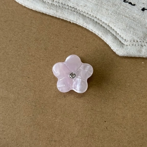 Makroaufnahme einer rosa Blumen-Haarklammer mit Strass und Perlmutt-Effekt auf Papier