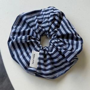Detailed shot of striped blue and white scrunchie with a handmade woven label